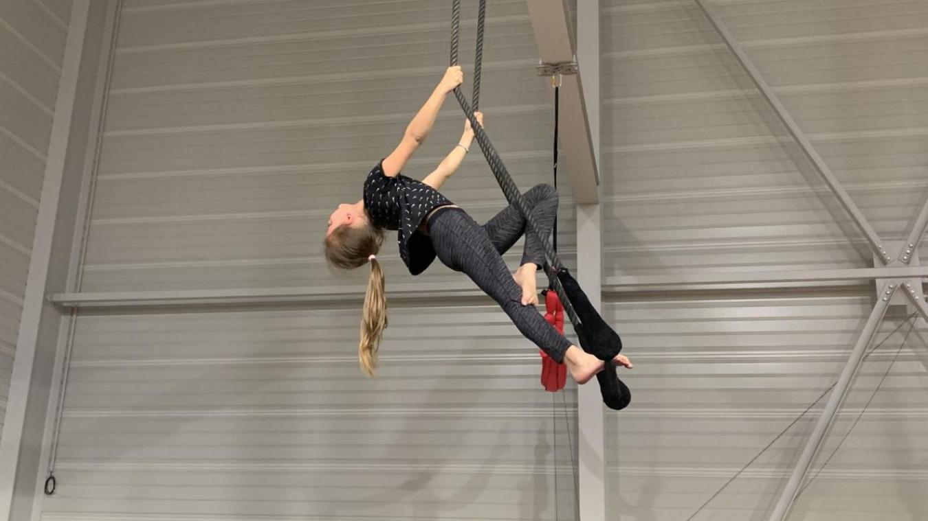 Léna réalise une souplesse arrière sur le trapèze le plus haut.