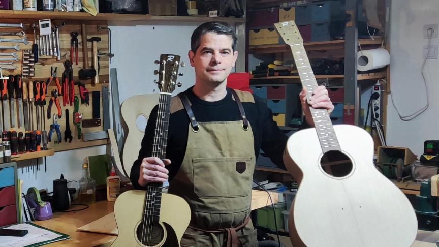 Julien Regnard présente une guitare terminée et une autre en cours dans son atelier à Villy-le-Pelloux.
